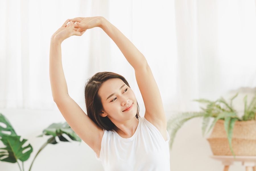 Lady stretching in a nicely lit studio with plants